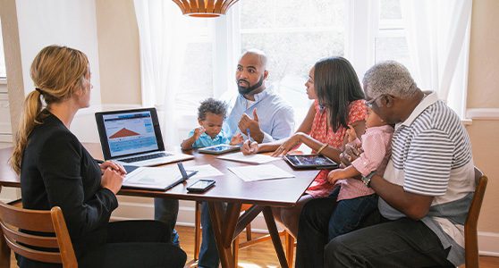 Uma fotografia que mostra corretora de seguros em reunião com uma família fazendo adesão ao seguro de pessoas