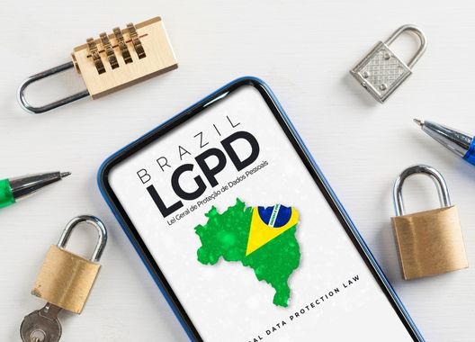 Uma fotografia de um celular com a escrita "Lei Geral de Proteção de Dados" e o mapa do Brasil, ao redor alguns cadeados simbolizando a privacidade de dados