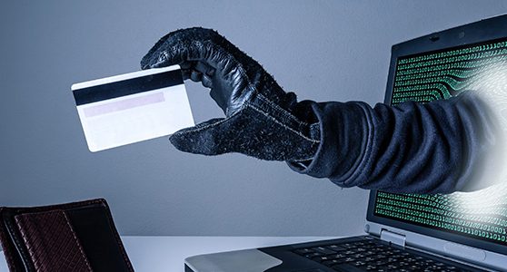 Uma fotohgrafia de uma mão com um cartãao de crédito saino de dentro da tela do computador