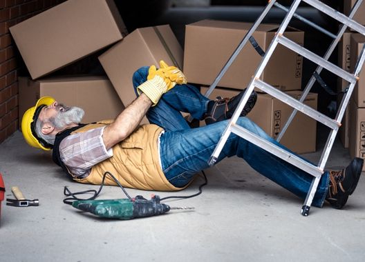 Fotografia de funcionário agarrado a perna com dor após cair de escada mostrando a importância do seguro de acidentes pessoais