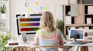 designer de agência de publicidade trabalhando sentada em mesa com monitor mostrando paletas de cores