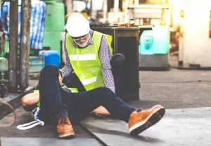 trabalhador caído após danos corporais amparado por colega em construção.