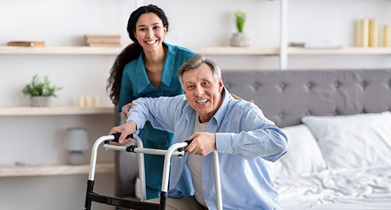 uma fotografia mostrando fisioterapeuta e paciente idoso com andador ilustrando as diferenças entre invalidez parcial e permanente