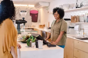 dona de microempresa recebendo cliente em cafeteria