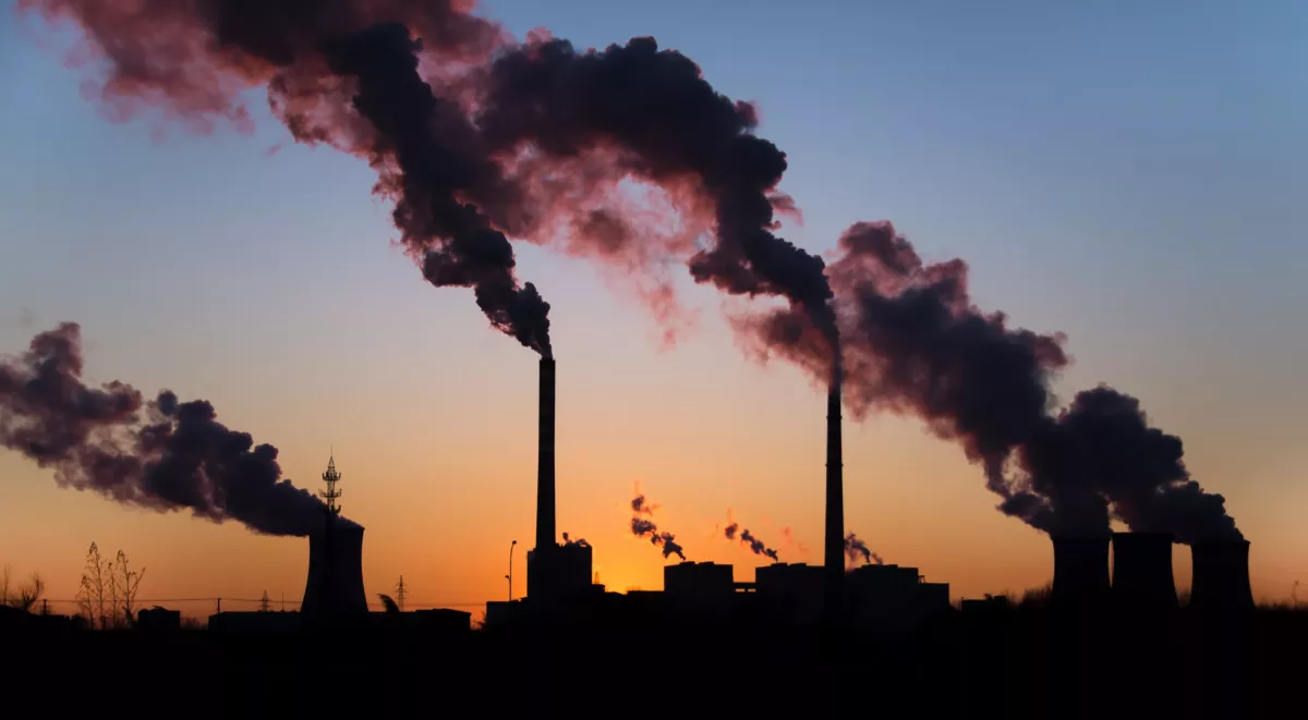 chaminé industrial soltando fumaça com céu cinzento ao fundo