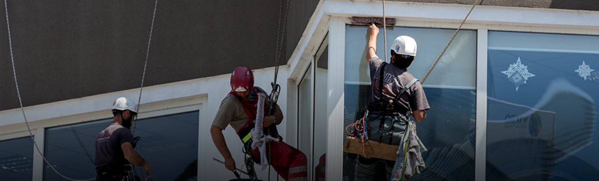 Uma imagem que ilustra homens limpando janelas de prédios