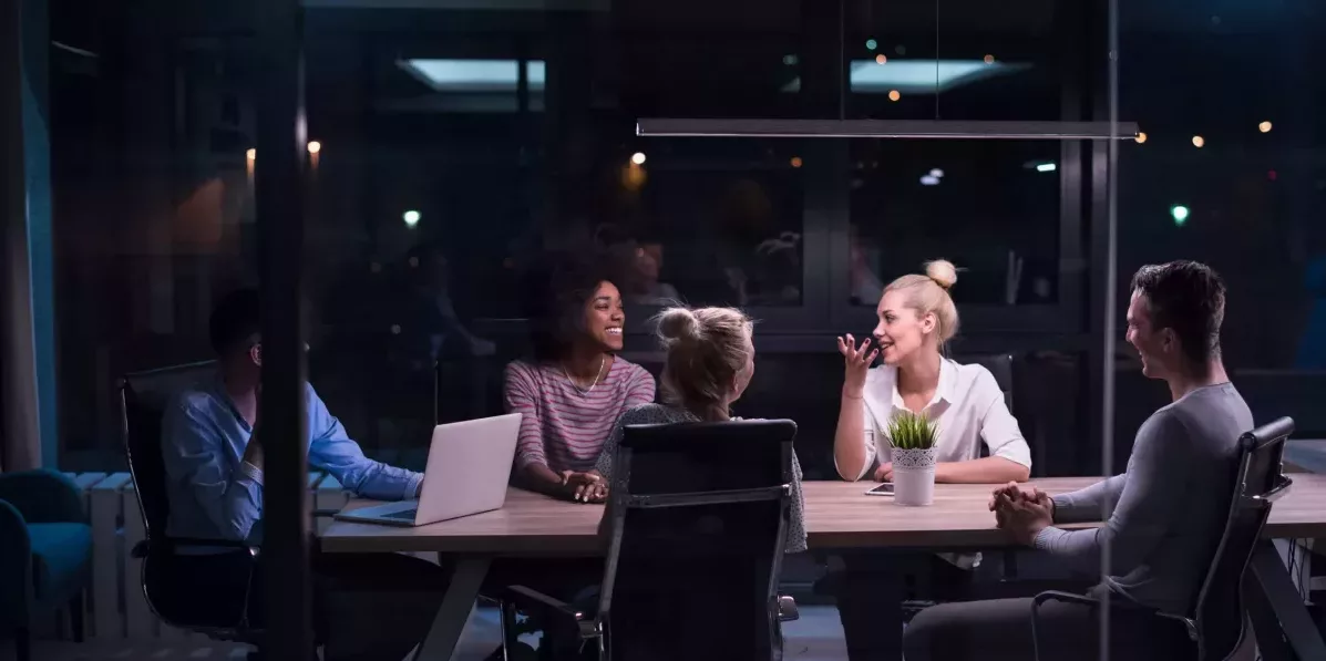 pessoas de empresa de pequeno porte reunidas em sala de reunião à noite