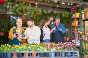 Lojistas e clientes em pequena loja de flores e plantas conversando.