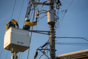 técnicos fazendo manutenção em cabos e poste de energia após queda de energia